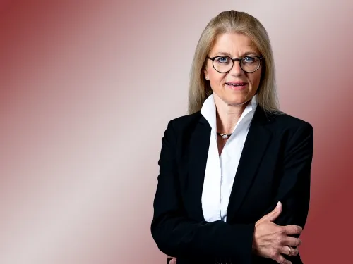 Porträt einer blonden Frau mit weißem Hemd und schwarzem Blazer.