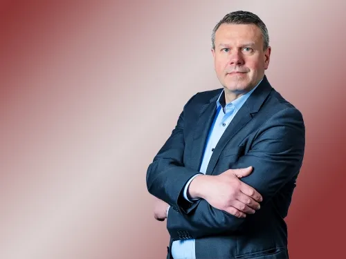 Porträt eines Mannes mit blauem Blazer und verschränkten Armen.