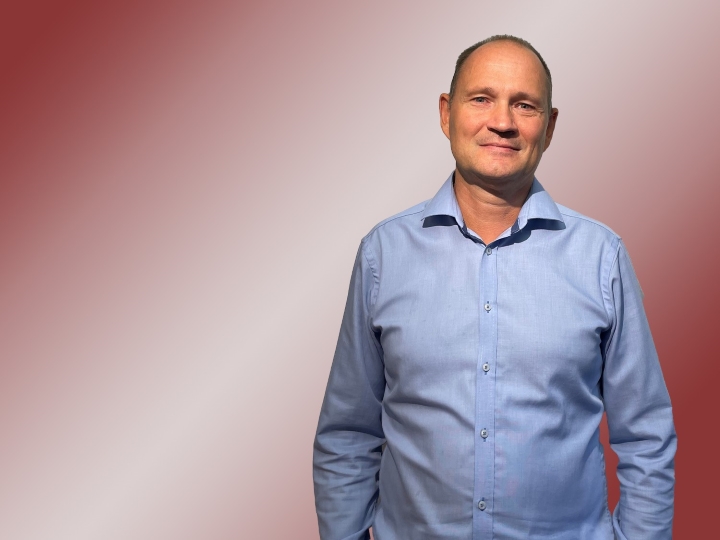 Porträt eines Mannes mit hellblauem Hemd und Glatze.