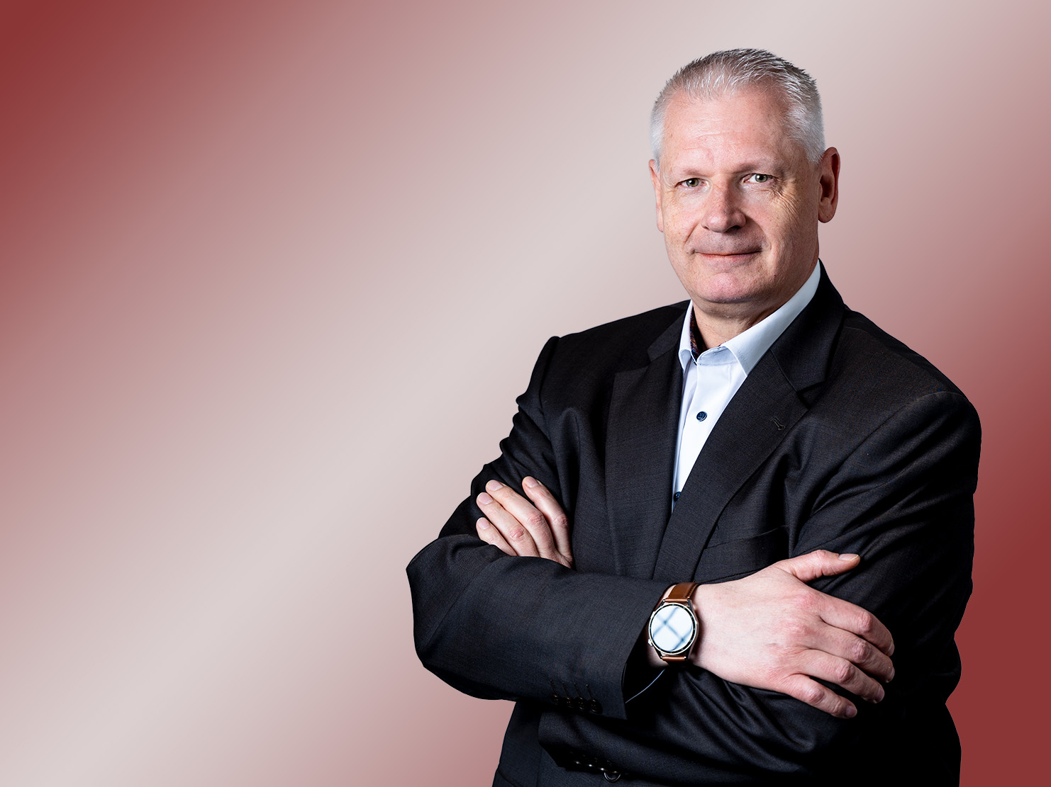 Porträt eines Mannes mit schwarzem Blazer und grauen Haaren.