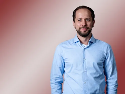 Porträt eines Mannes mit hellem, blauem Hemd.