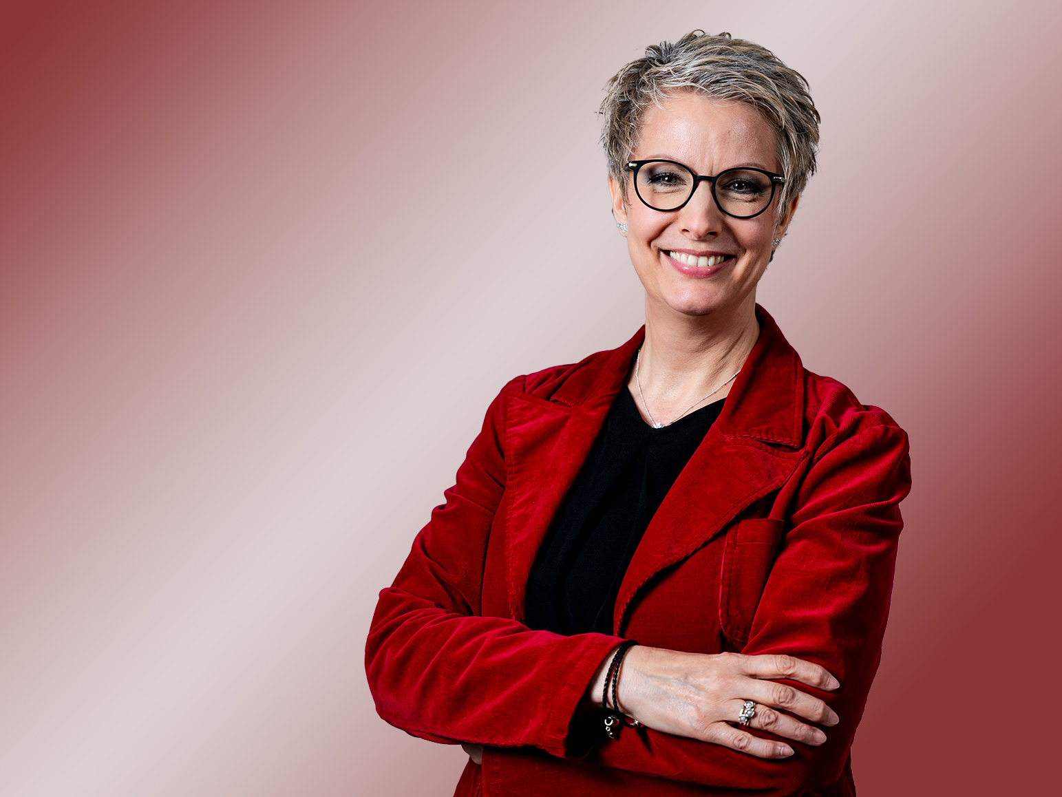Porträt einer Frau mit Brille und rotem Blazer.