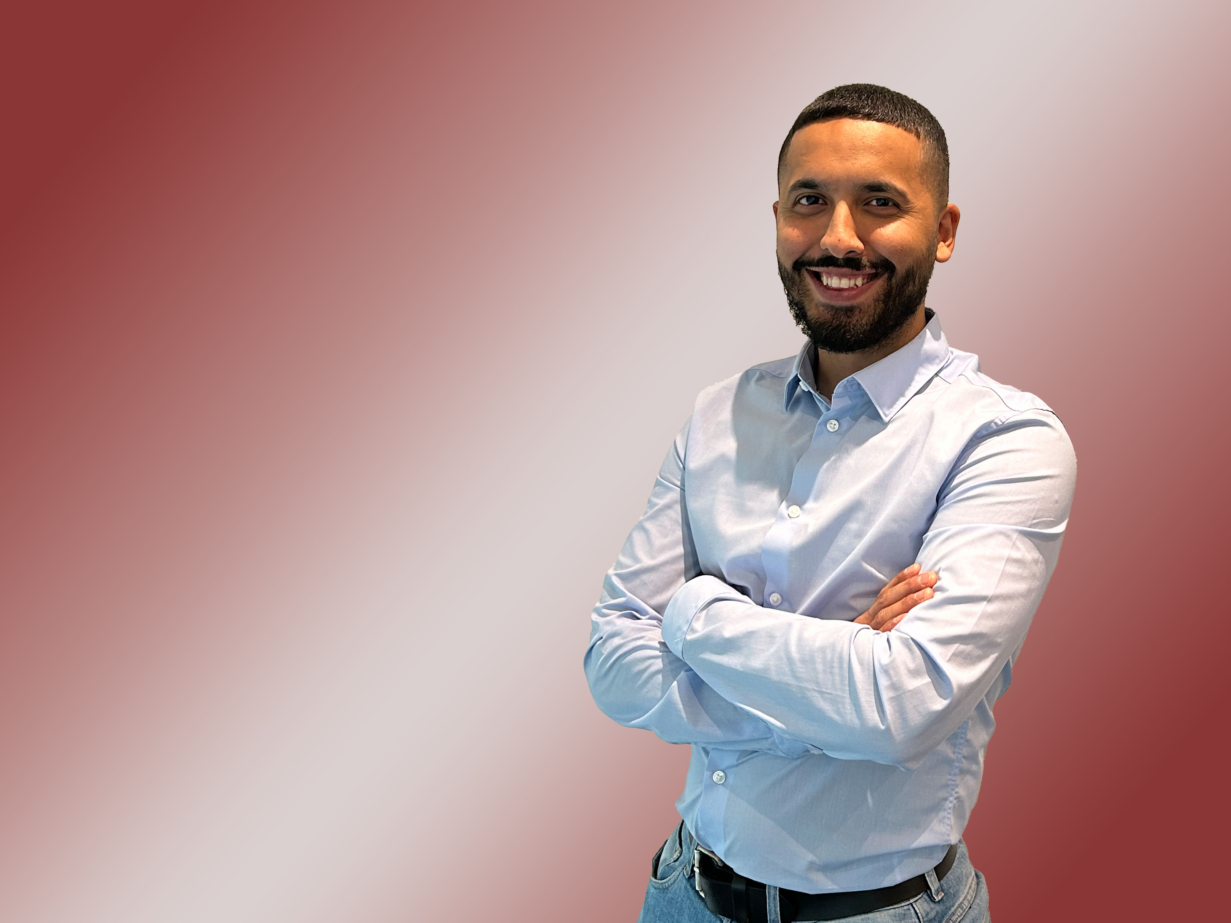 Porträt eines Mannes mit braunen Haaren, kurzem Bart und weißem Hemd.