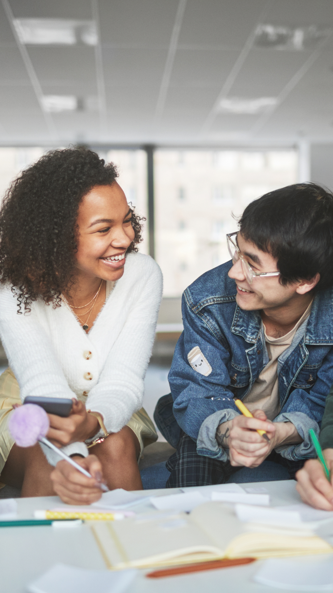 Ein Mann und eine Frau stehen an einem Schreibtisch und schauen sich lachend an.