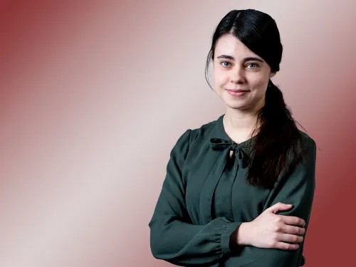 Porträt einer brünetten Frau mit dunkelgrüner Bluse.