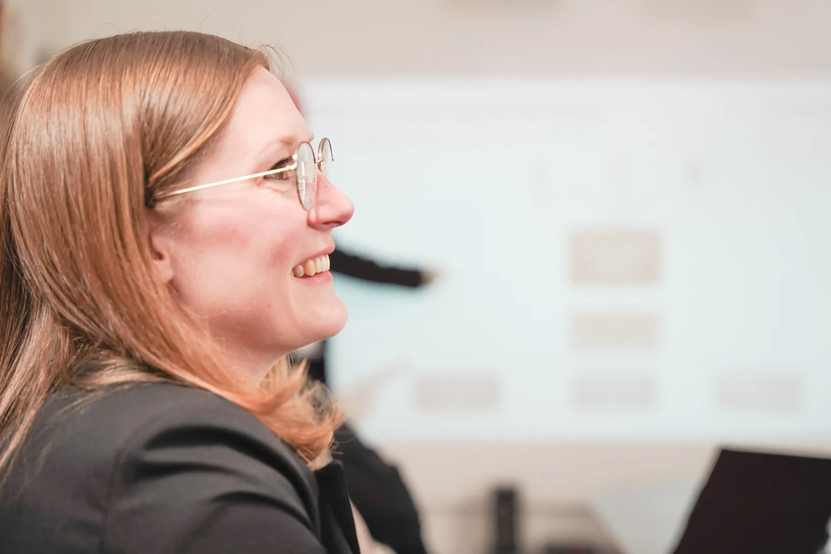 Eine Frau ist seitlich zu sehen und lächelt.