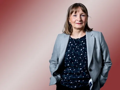 Porträt einer Frau mit grauem Blazer und gemusterten Shirt.