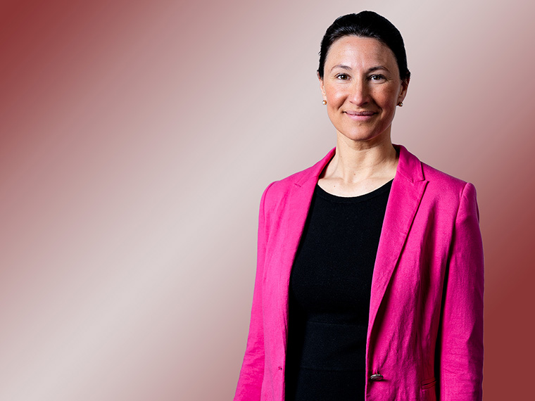 Porträt einer brünetten Frau mit pinkem Blazer.