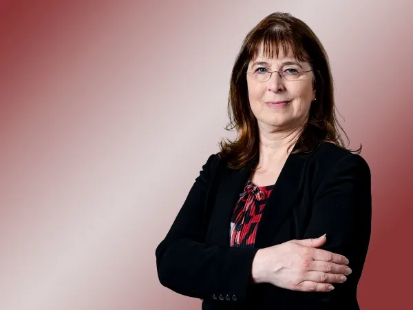 Porträt einer Frau mit Brille und schwarzem Blazer.