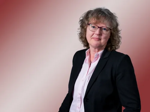 Porträt einer Frau mit Brille und schwarzem Blazer.