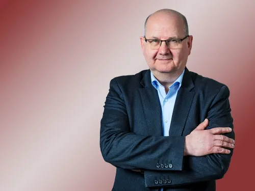 Porträt eines Mannes mit Brille und Blazer.