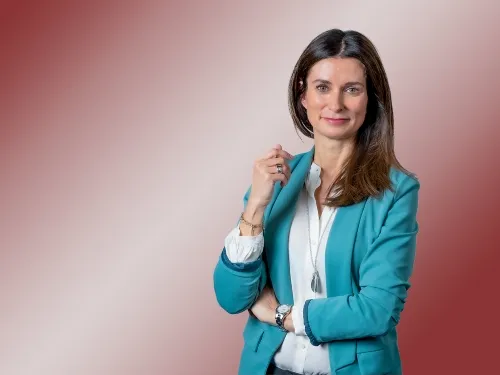 Porträt einer brünetten Frau mit türkisem Blazer.
