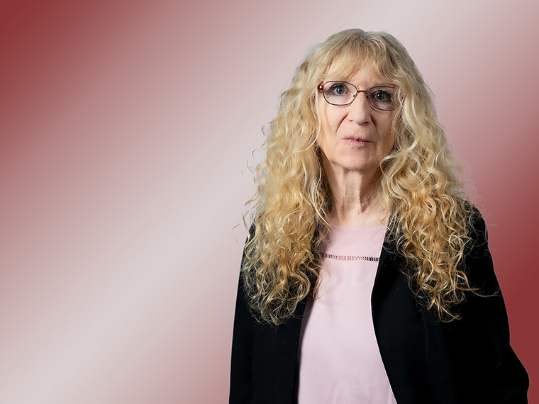 Porträt einer Frau mit brille und blonden Locken.