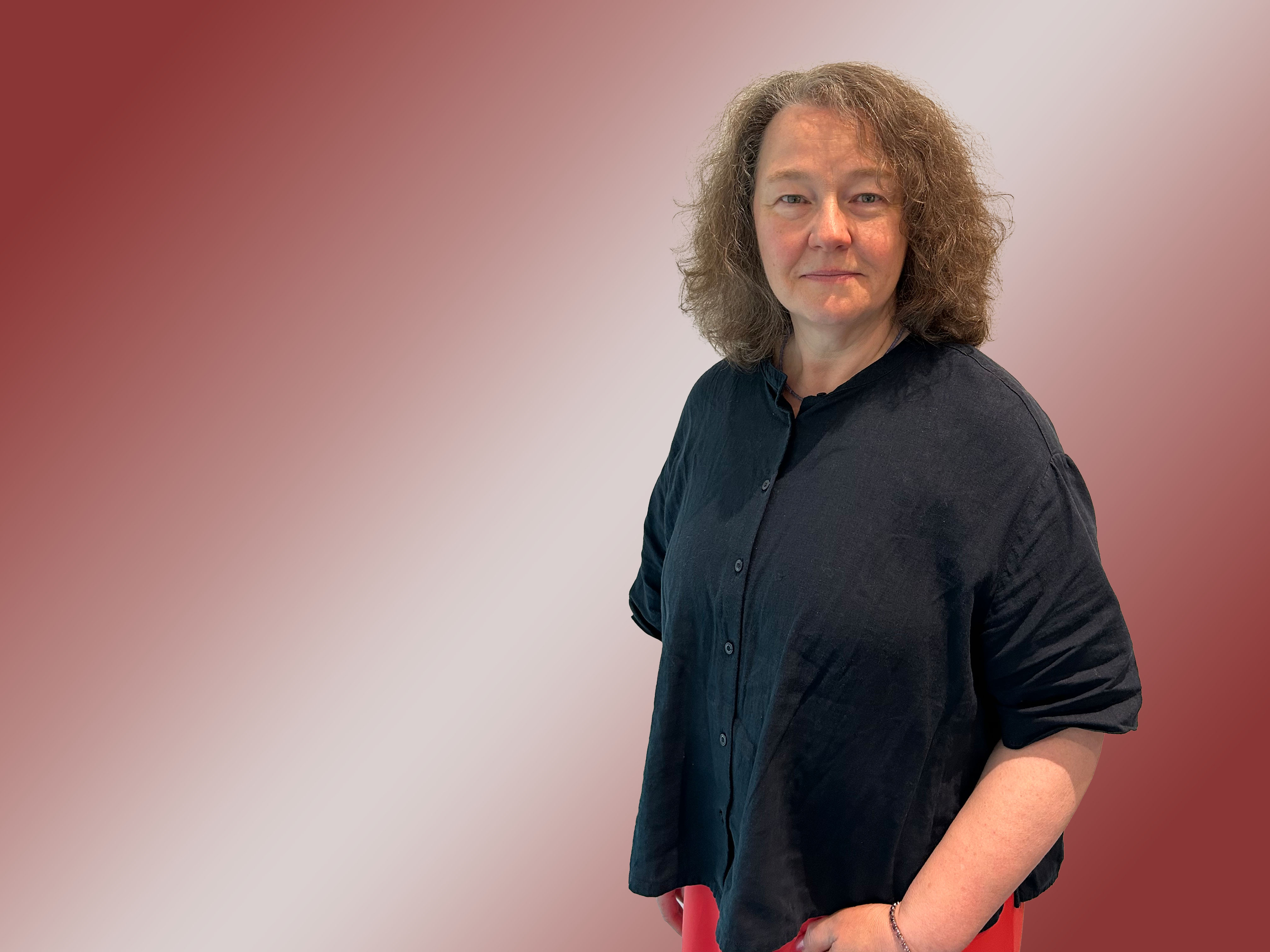 Porträt einer Frau mit Locken und dunkler Bluse.